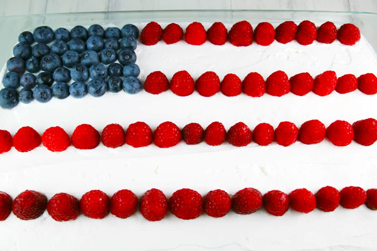 Top of no bake cake with cool whip and berries in a flag pattern.