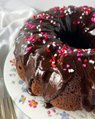 Chocolate Bundt Cake on a white plate with flowers.