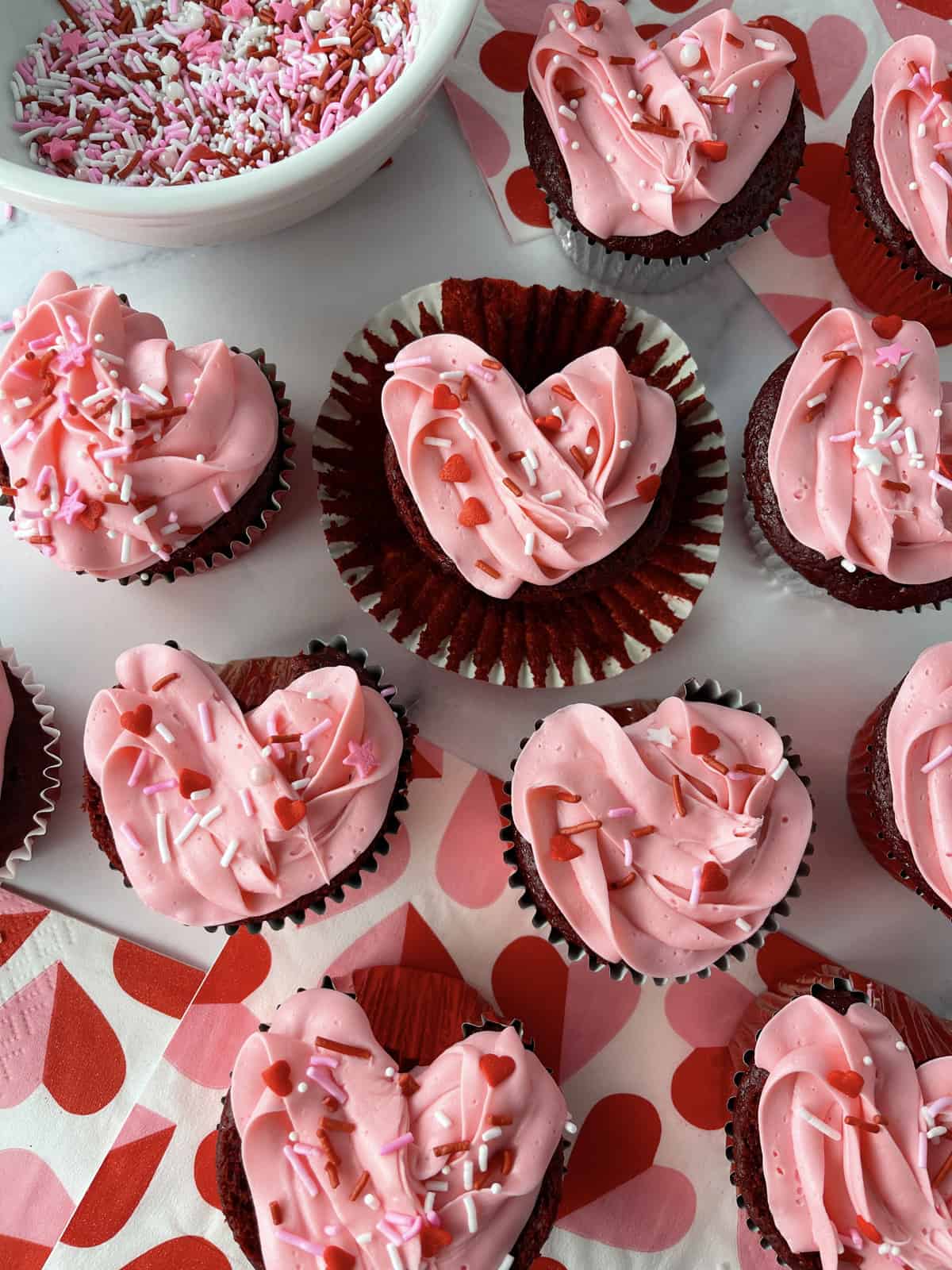 Valentine cupcakes on a table with heart napkins.