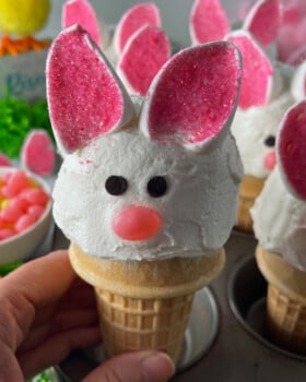 Easy Bunny Cupcakes with Marshmallow Ears in a cupcake pan with Easter decorations in the background.