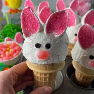 Easy Bunny Cupcakes with Marshmallow Ears in a cupcake pan with Easter decorations in the background.