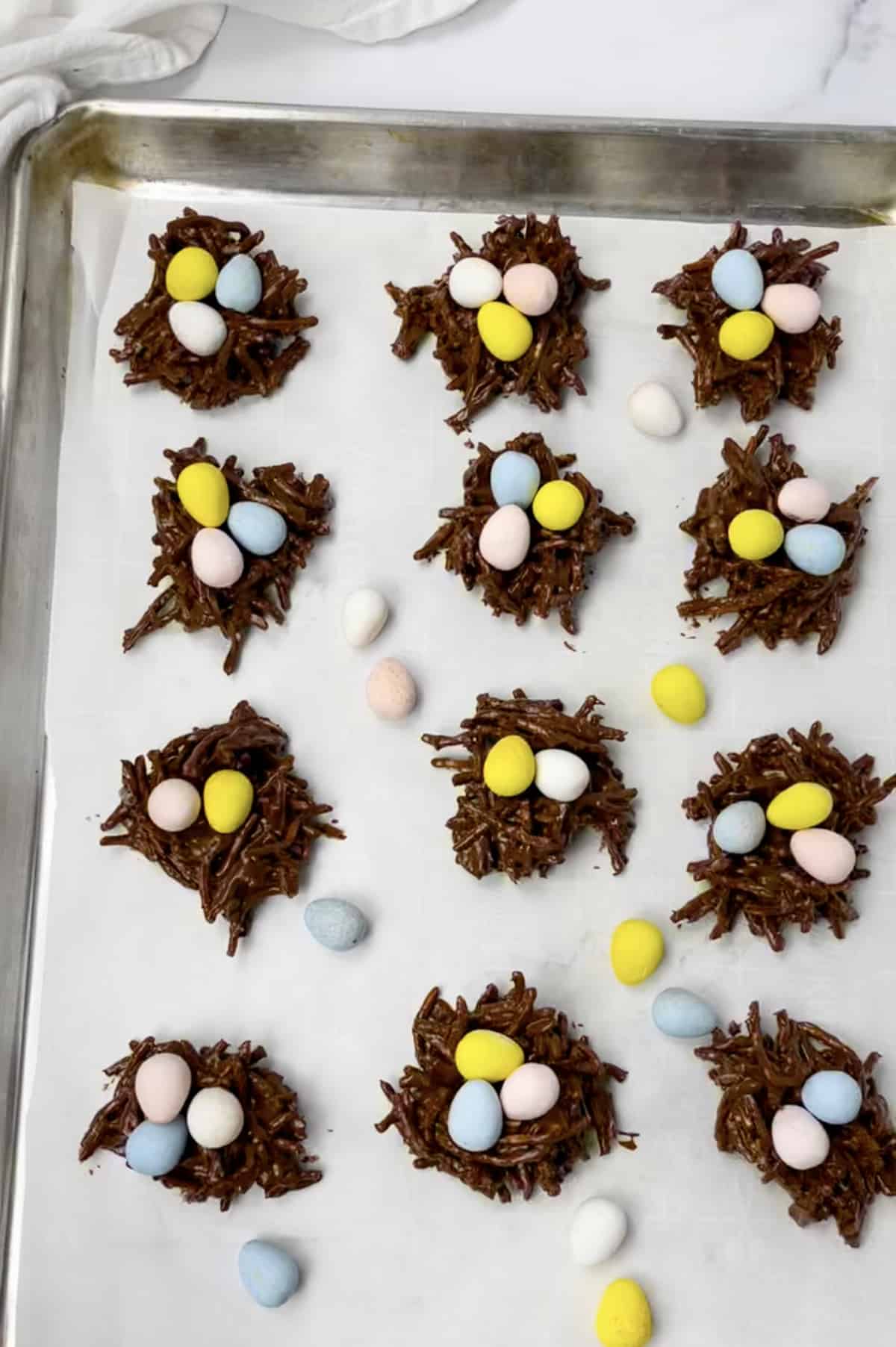 Cookie sheet with parchment paper and bird's nest cookies.