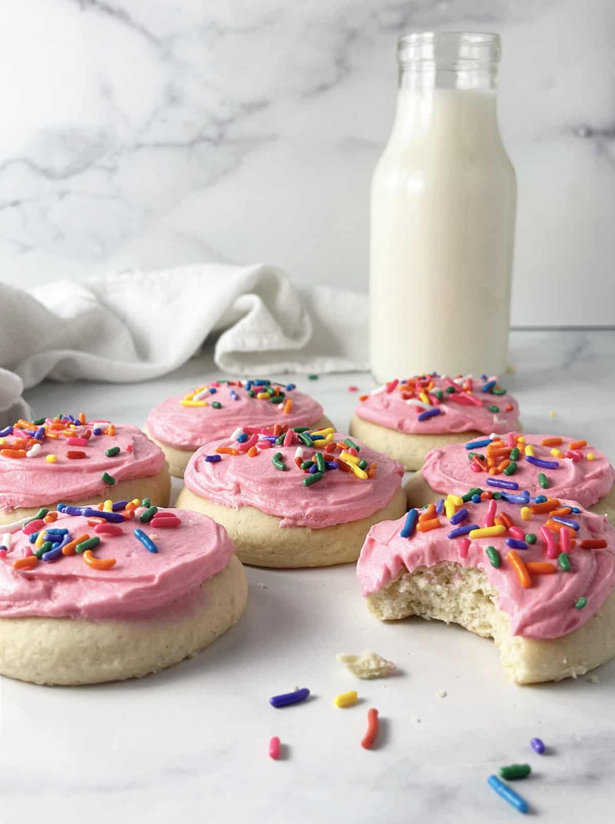 Soft sugar cookies with pink frosting on counter.