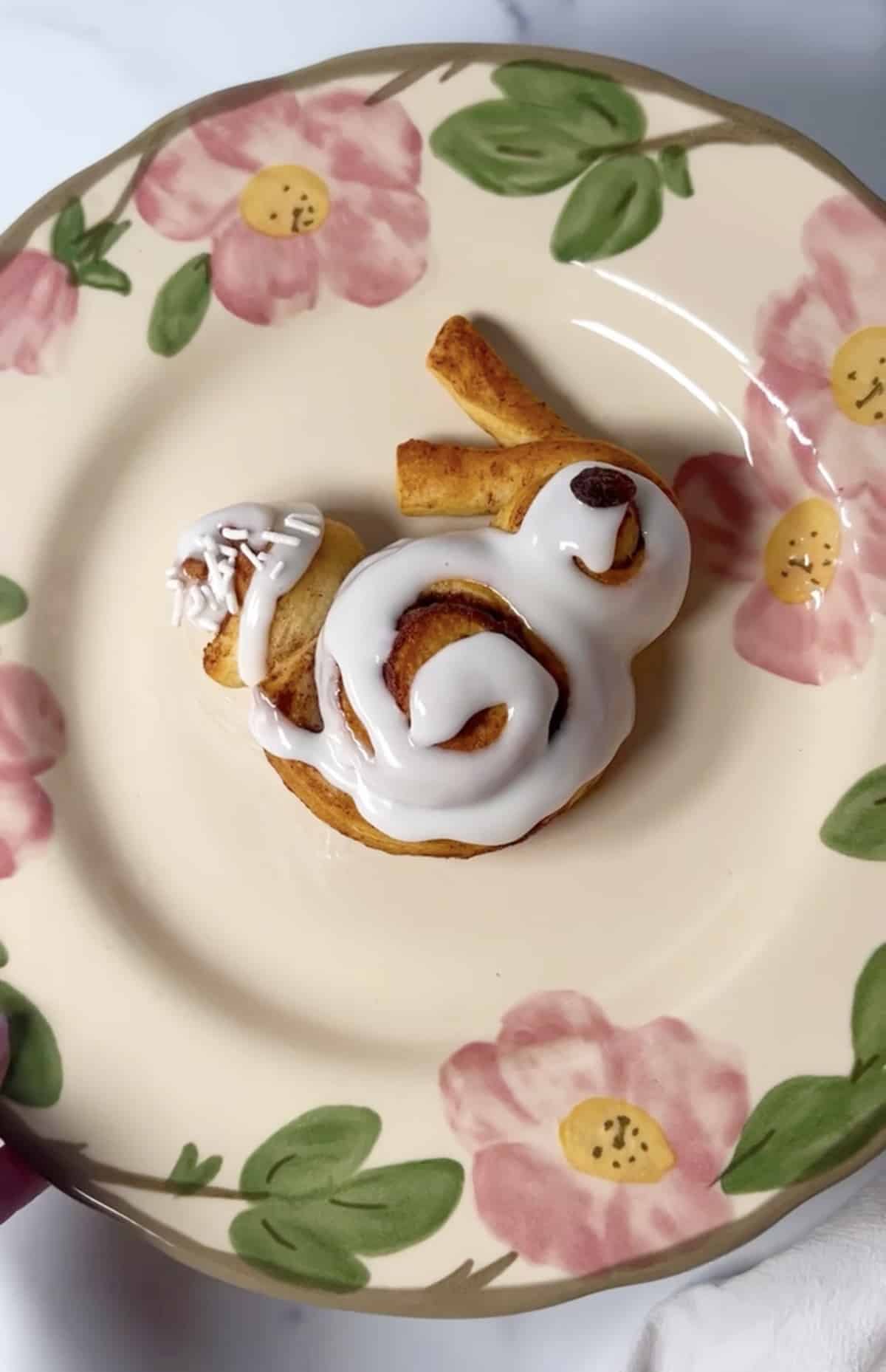 Flowered plate with one bunny shaped cinnamon roll.