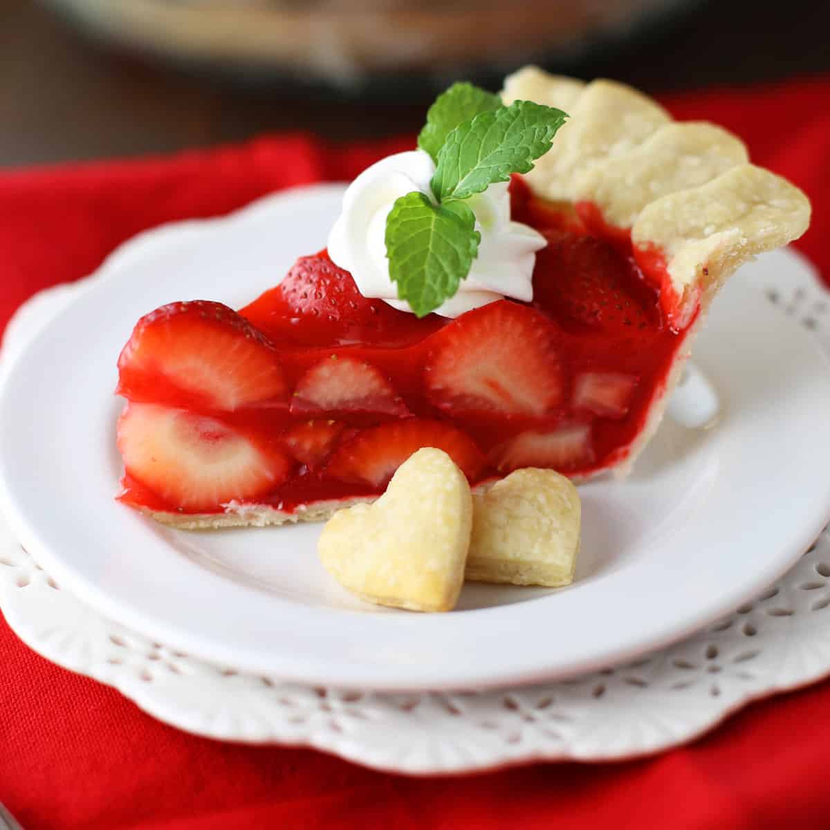 Strawberry pie on a white plate with mint leaf on top.