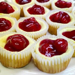 Mini cherry cheesecakes on a white platter.