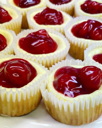 Mini cherry cheesecakes on a white platter.