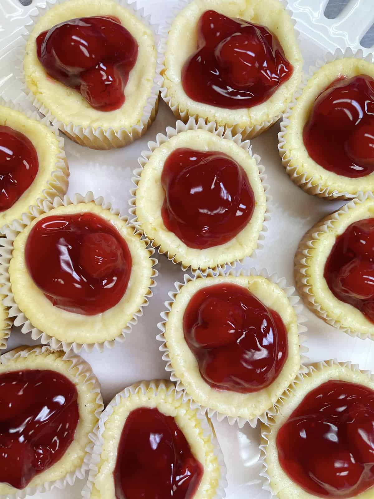 Mini cherry cheesecakes on a big white plate.