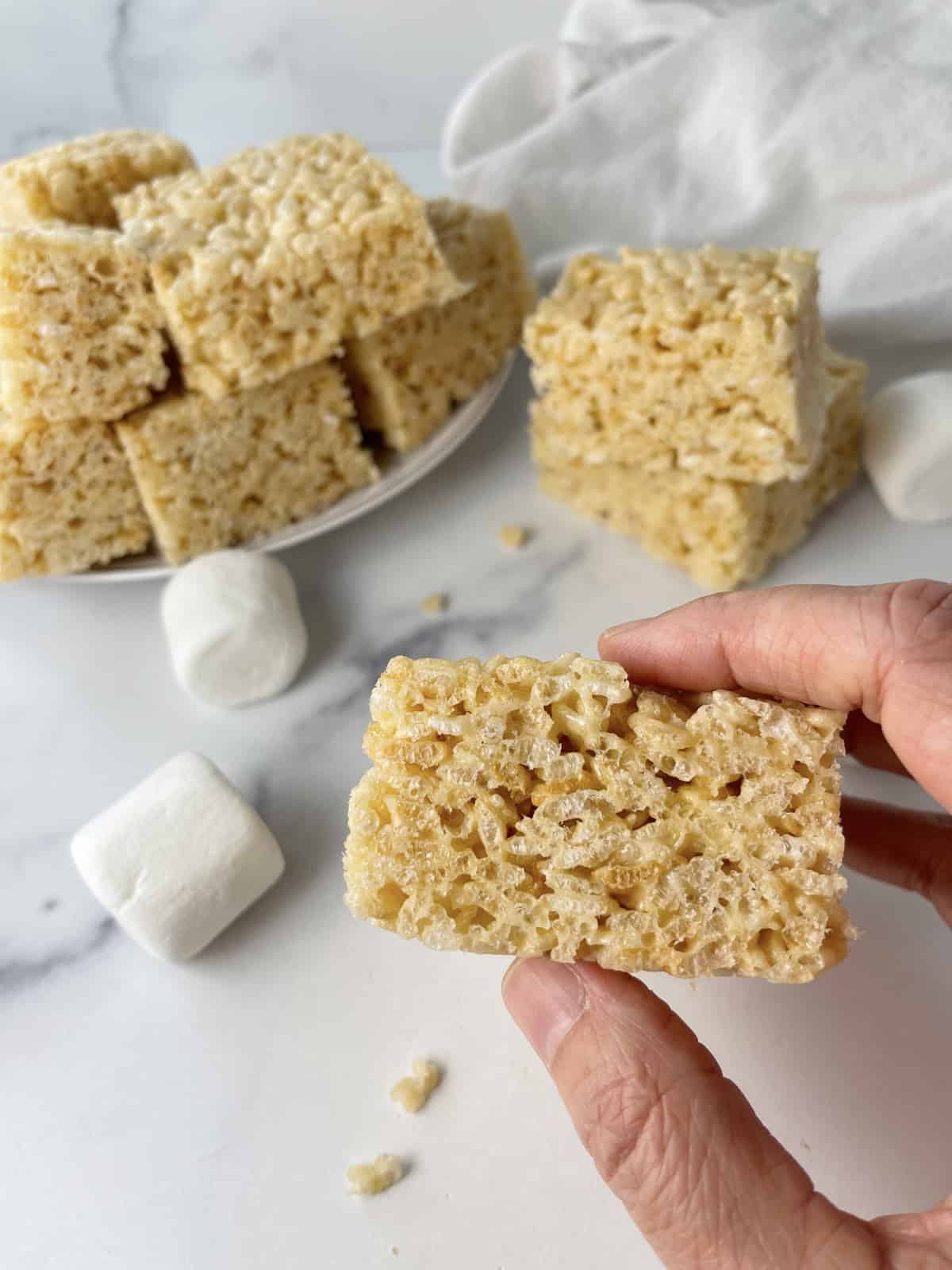 Hand holding a rice krispie treat square to show how thick it is.