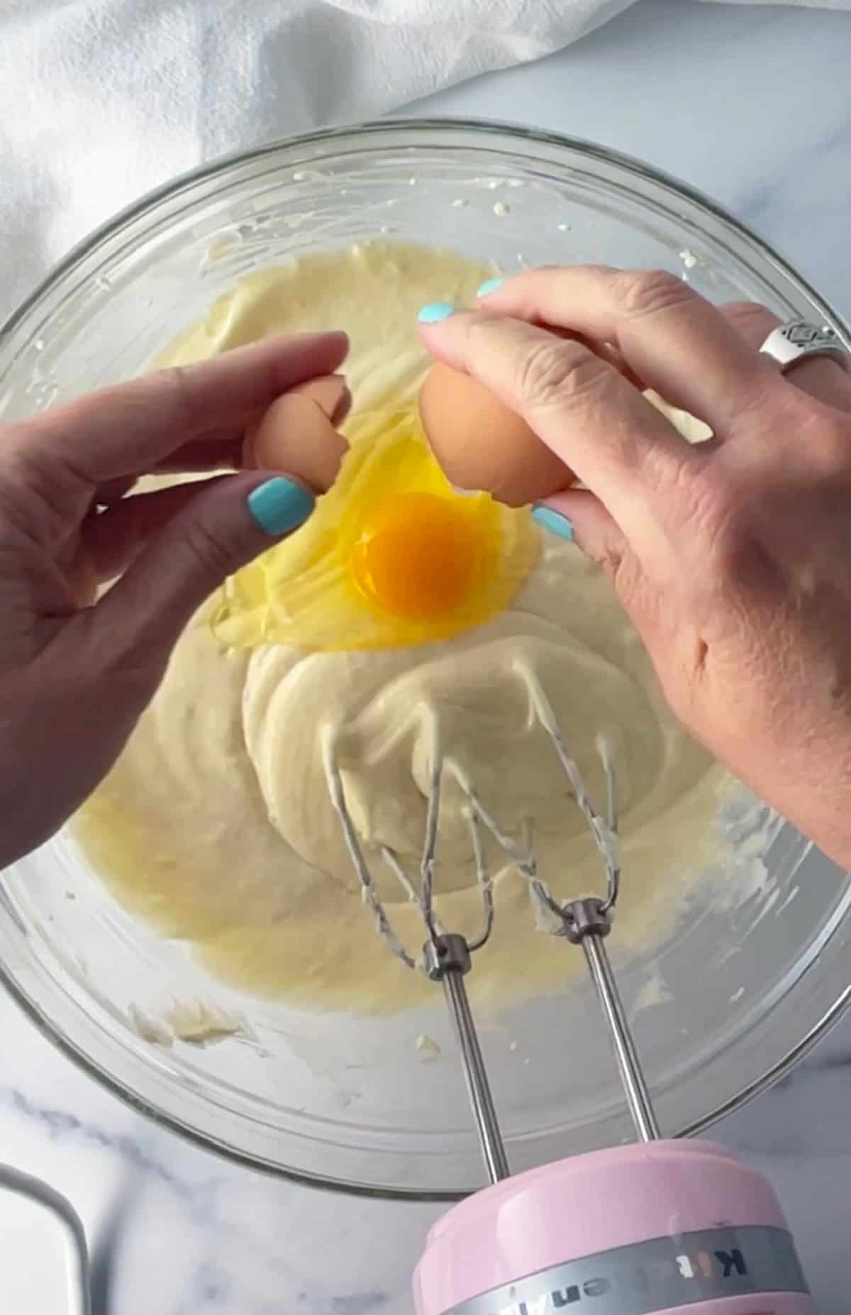 Cracking egg into cheesecake batter.