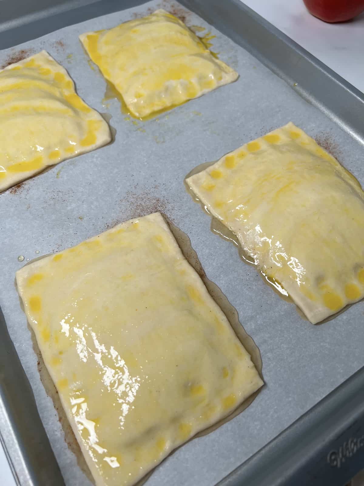 Cover apples with puff pastry rectangles and brush with egg wash.