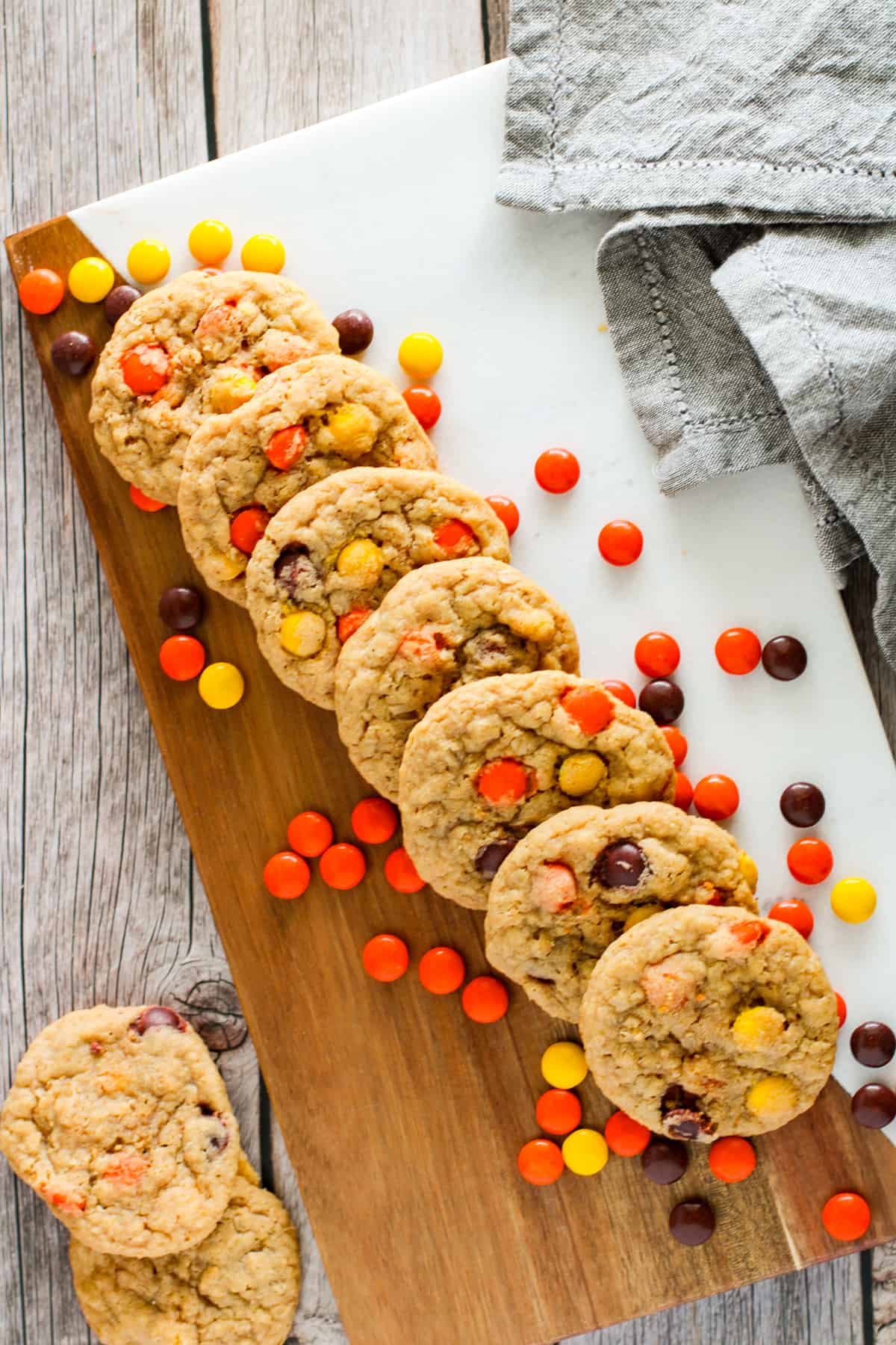 Cookies lined up on a cutting board with Reese's pieces candy.