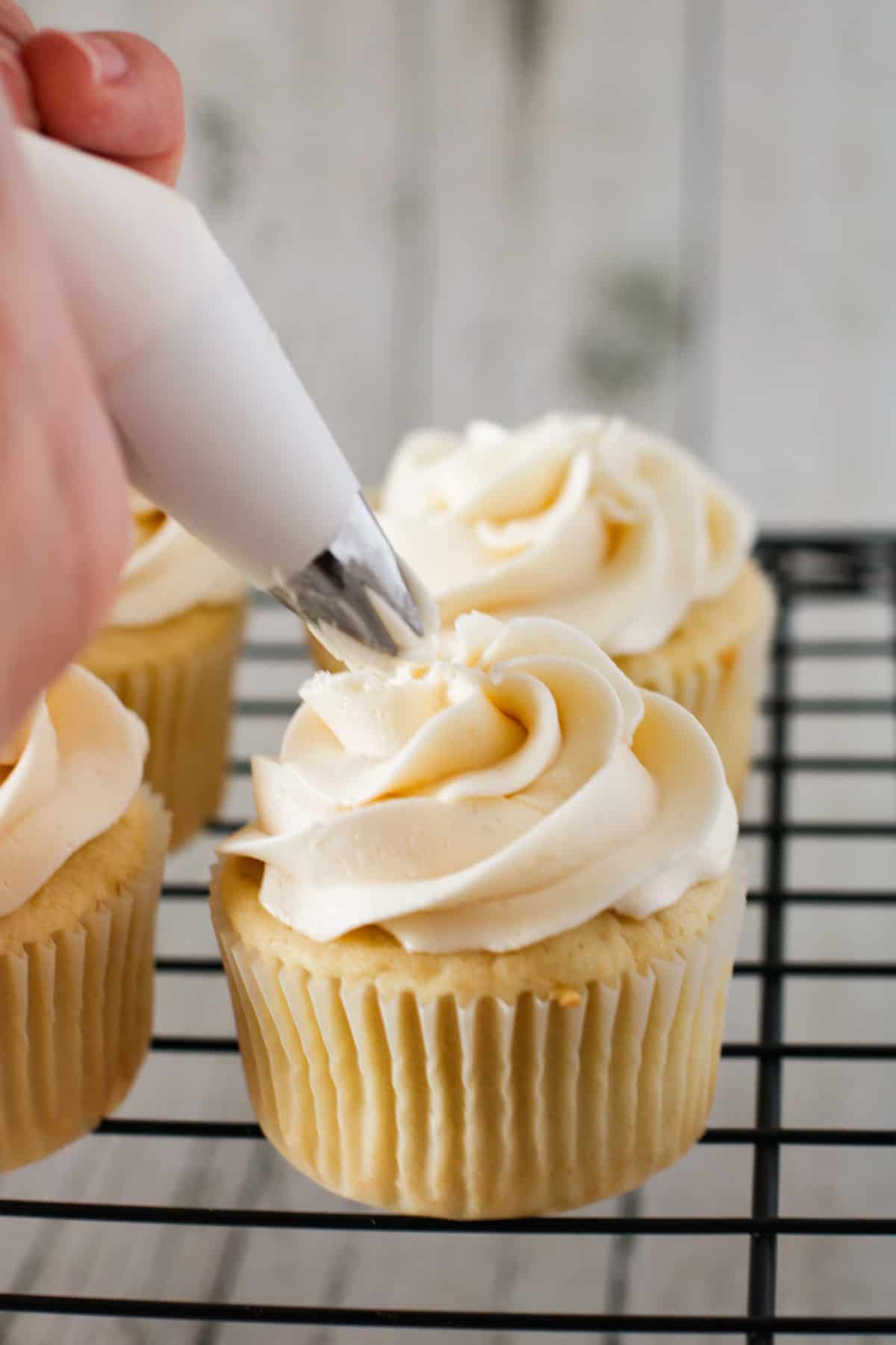 Frosting a vanilla cupcake with pastry tip.