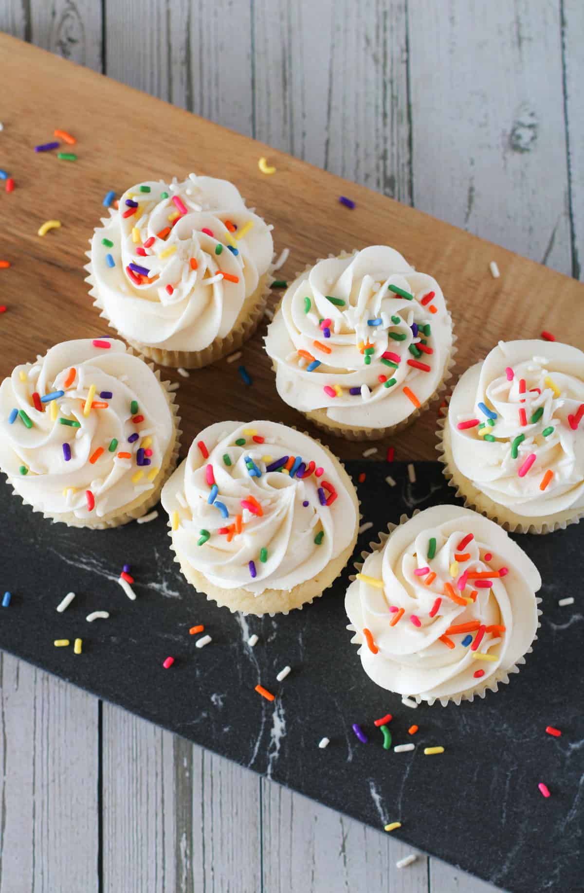 Homemade vanilla cupcakes on a cutting board.