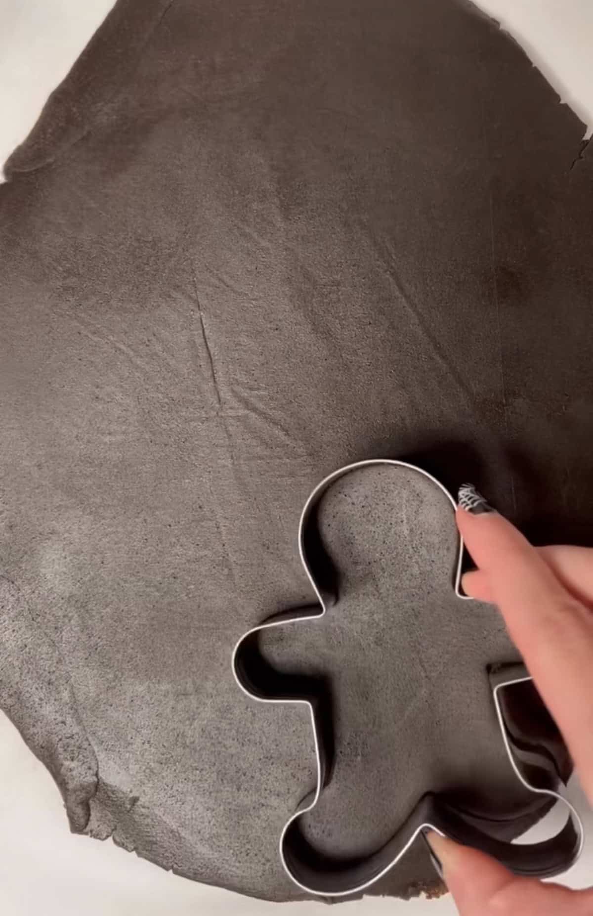 Gingerbread cookie cutter cutting dough.