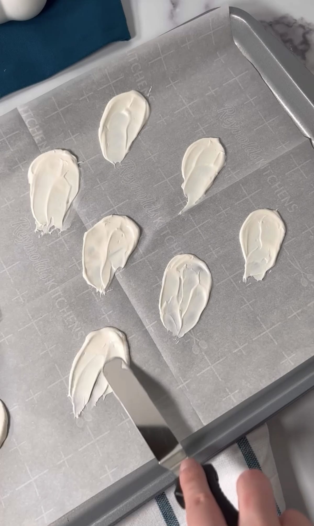 Making candy melt ghosts on a cookie sheet.