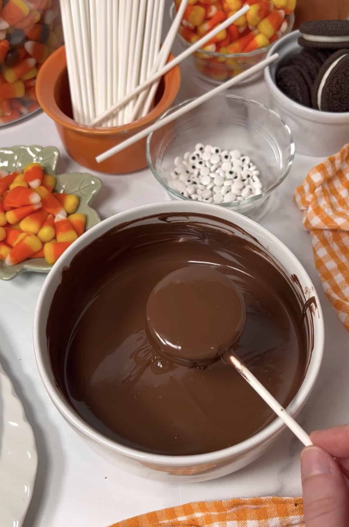 Dipping oreo cookies in melted chocolate almond bark.