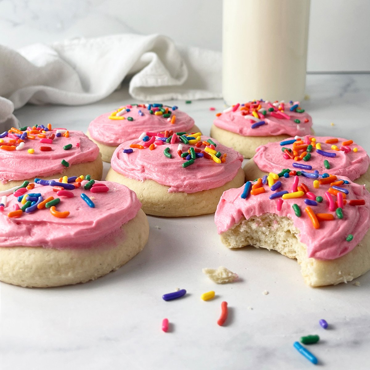 Copycat Lofthouse soft frosted sugar cookies on the counter with sprinkles.