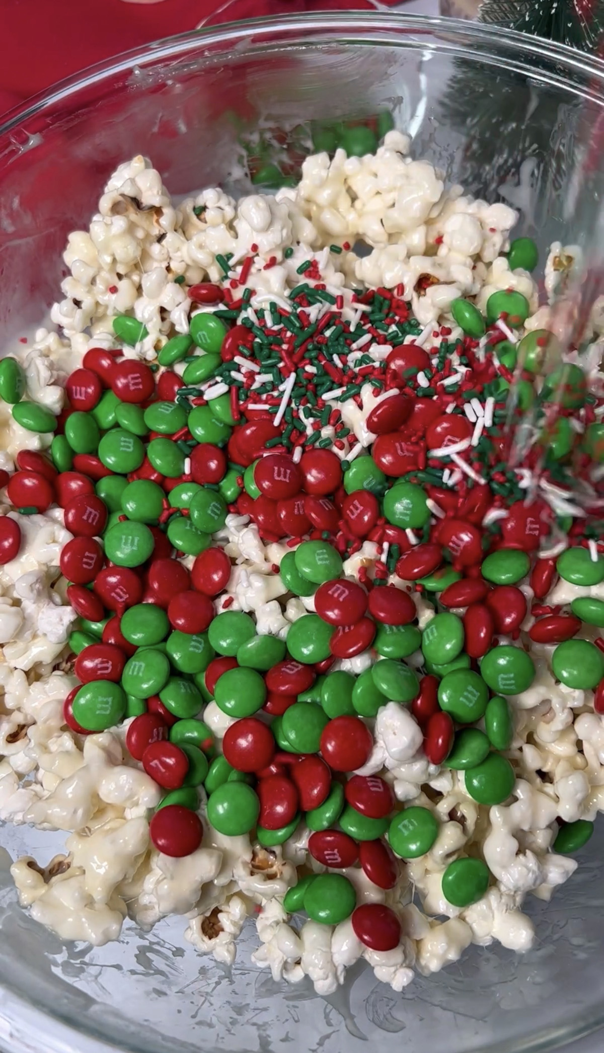 Mixing Christmas sprinkles into popcorn ball mixture.