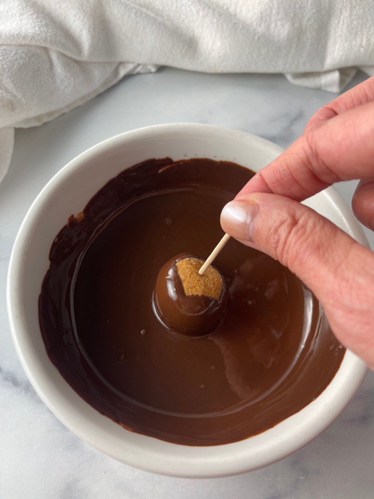 Dipping healthy buckeye candies in melted chocolate.