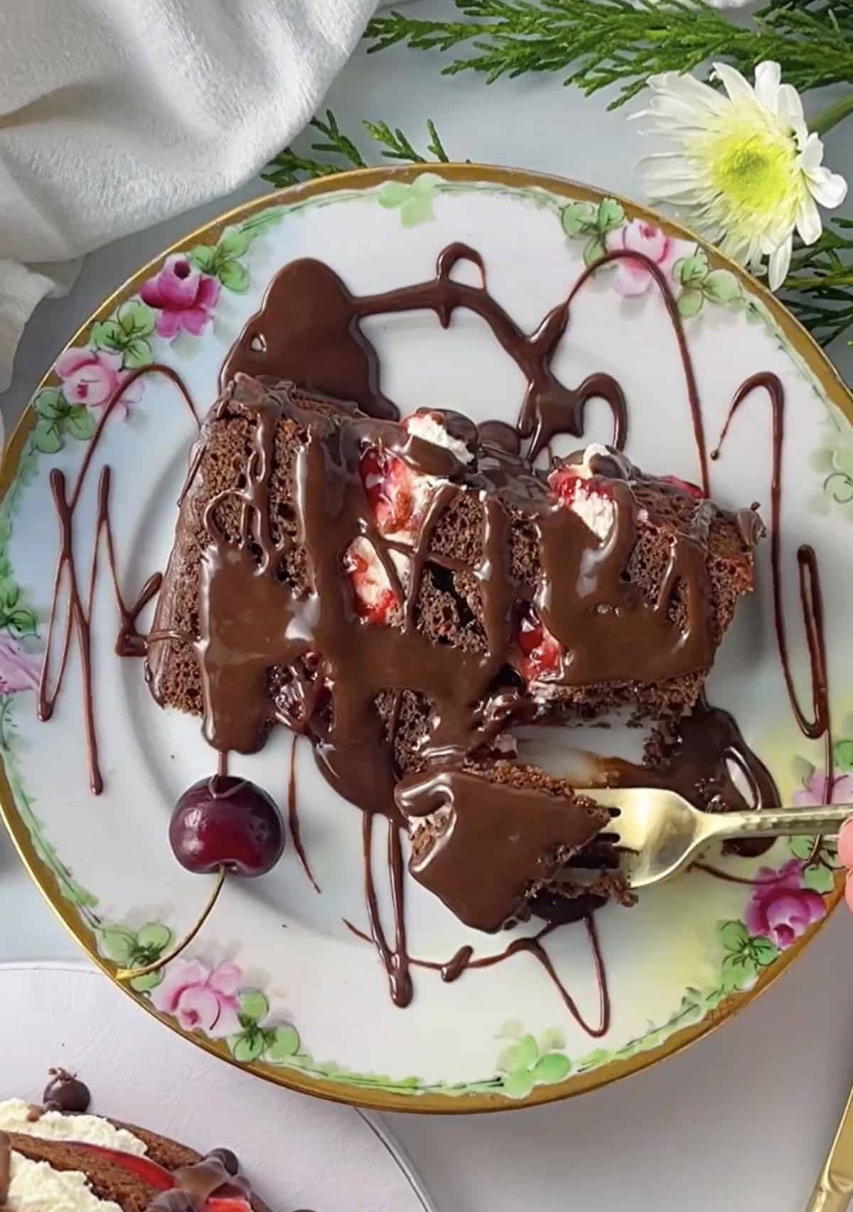 Slice of black forest cake drizzled with chocolate ganache.