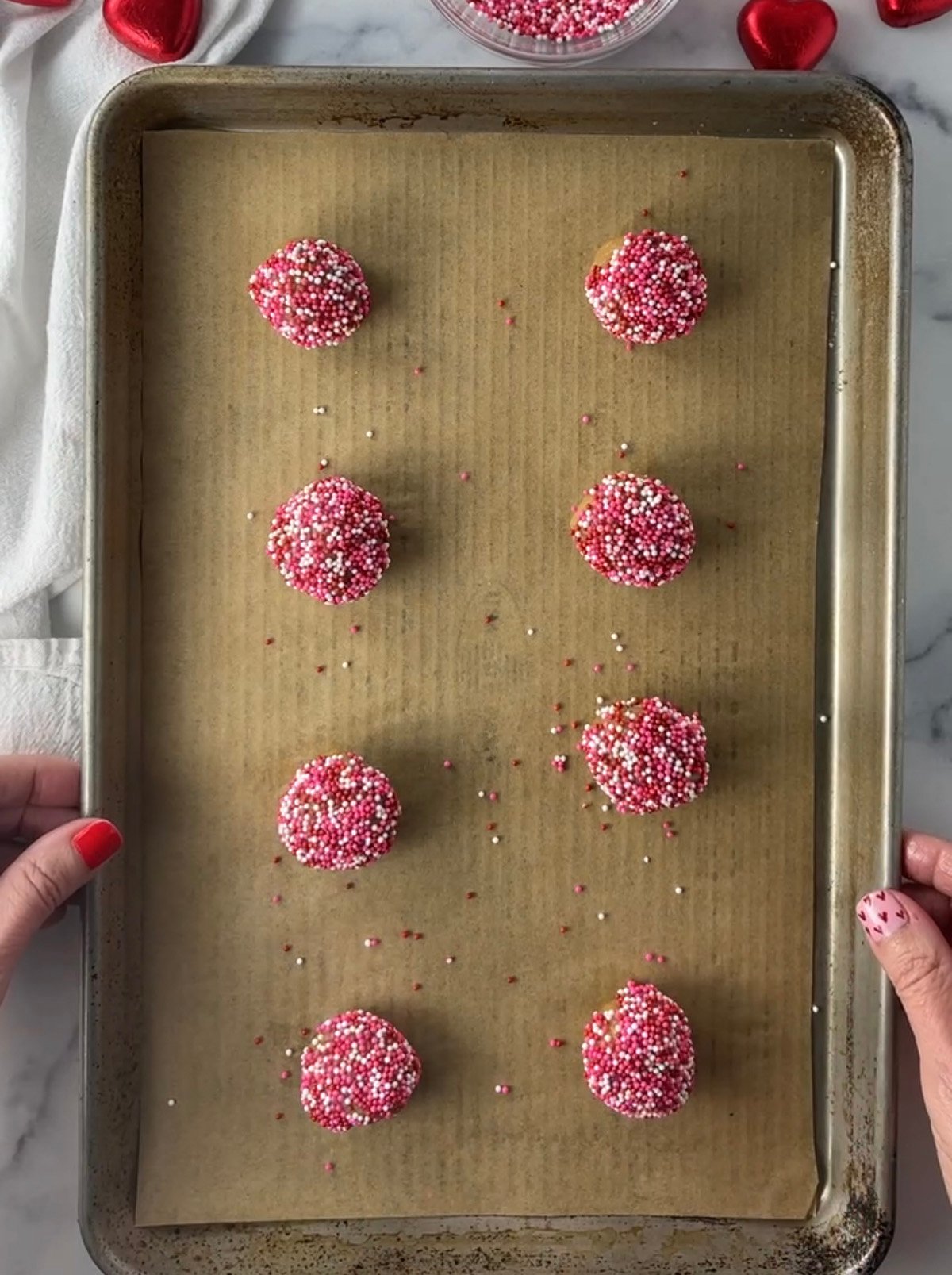Cookie dough ball with sprinkles on cookie sheet.