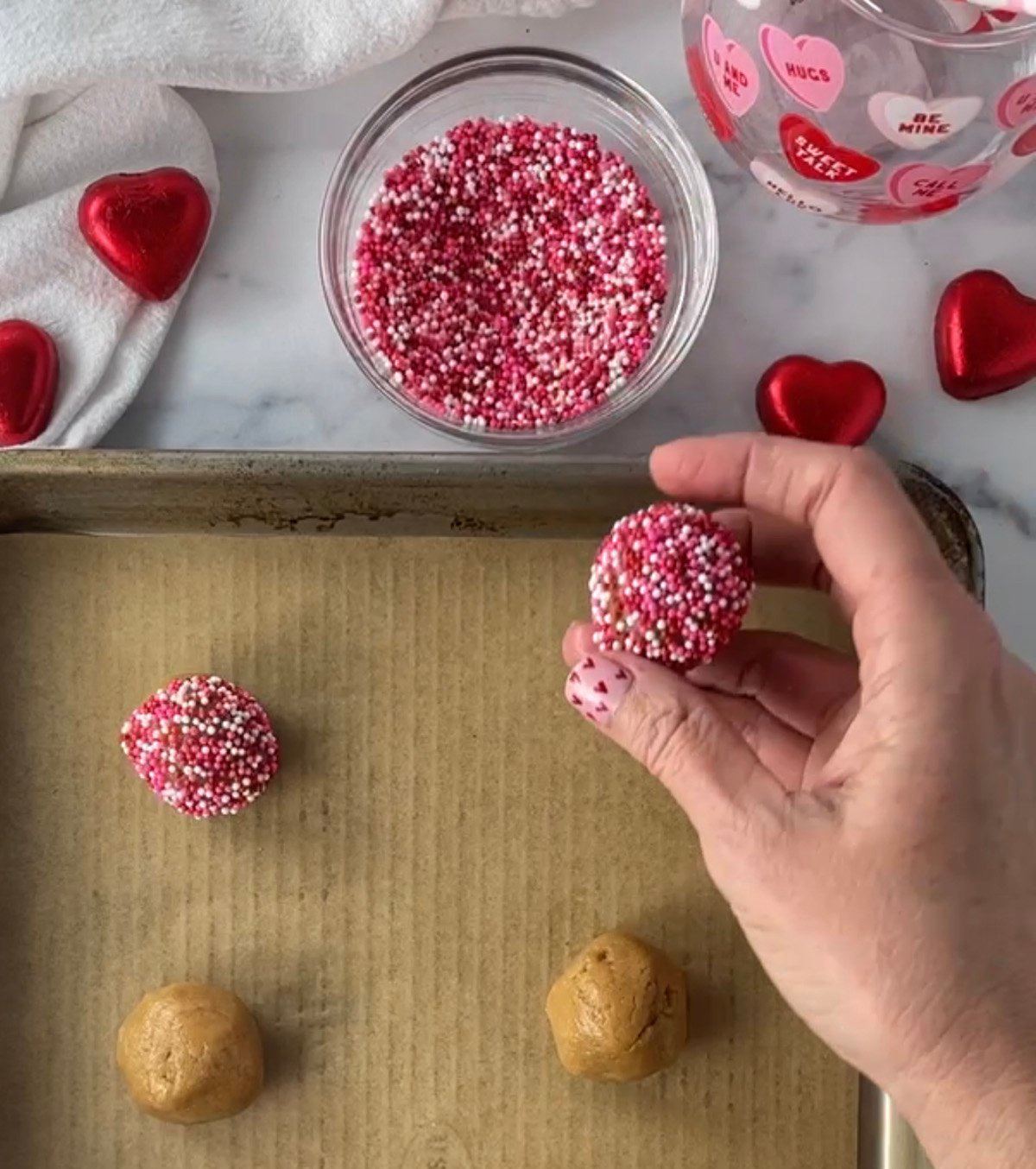 Rolling peanut butter cookie dough balls in sprinkles.