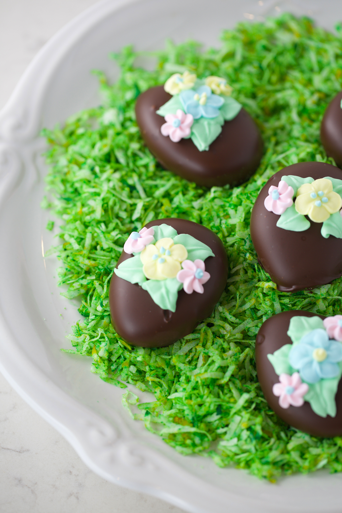Copycat Reese's Easter eggs on a white plate with green coconut grass.