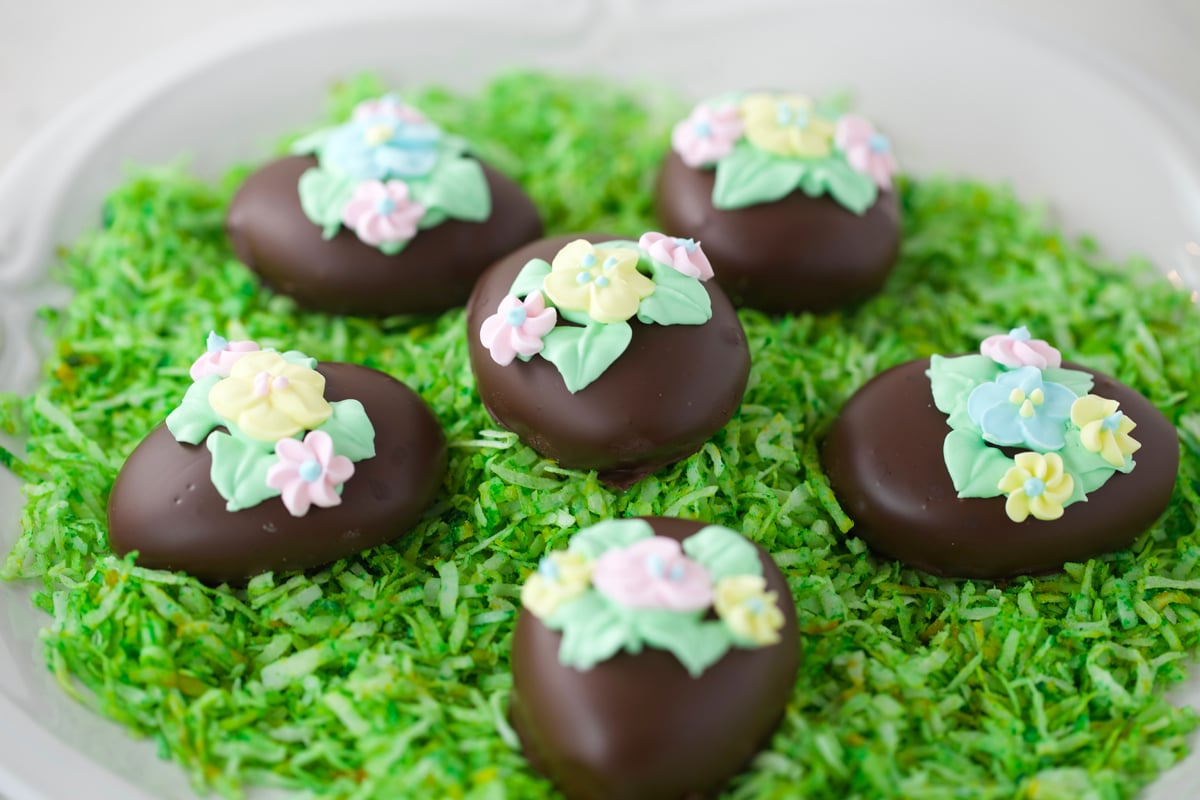 Chocolate Easter eggs on white plate with green colored coconut grass.