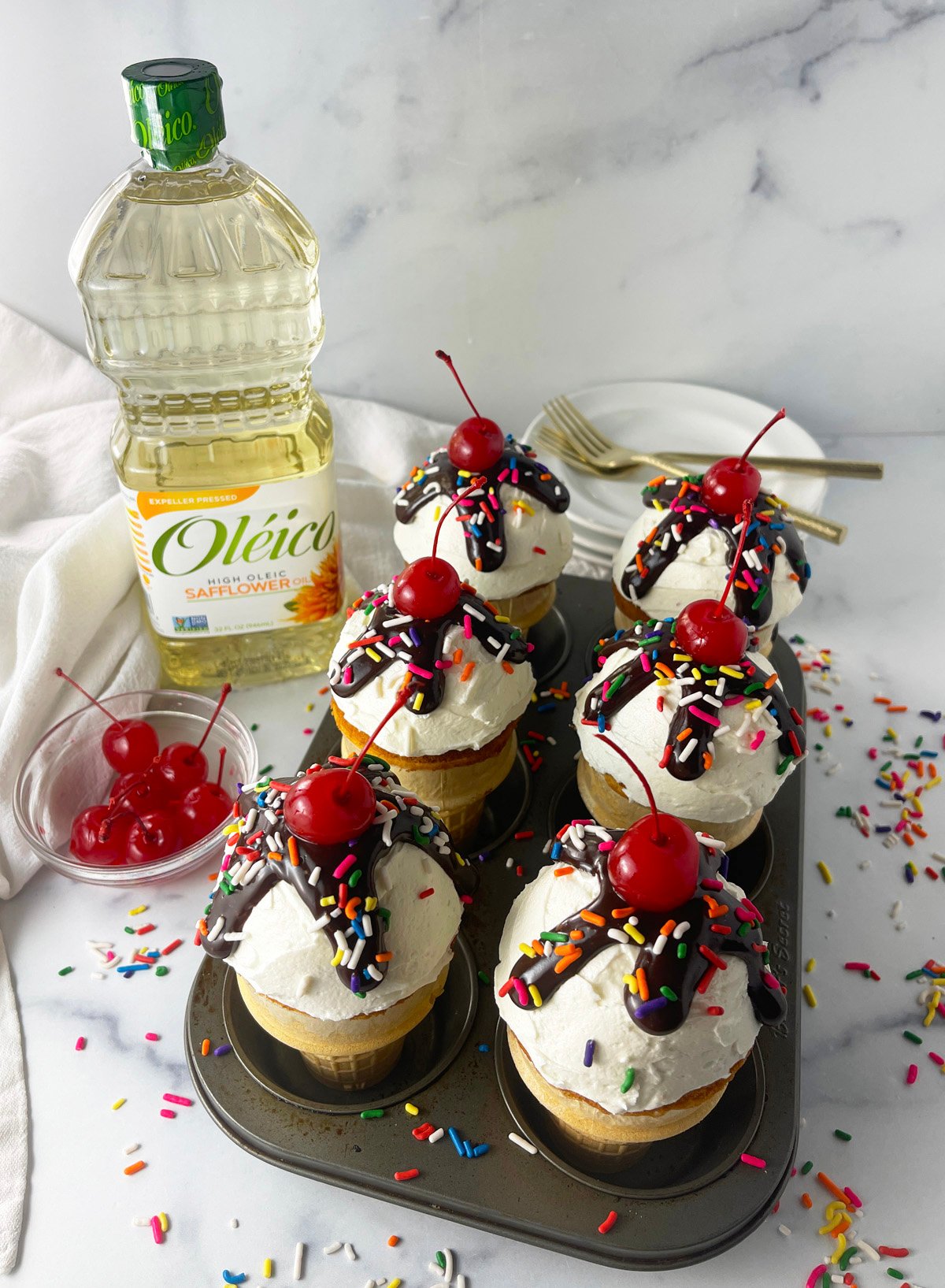 Ice cream cone cupcakes in a muffin pan with Oleico oil bottle in background.
