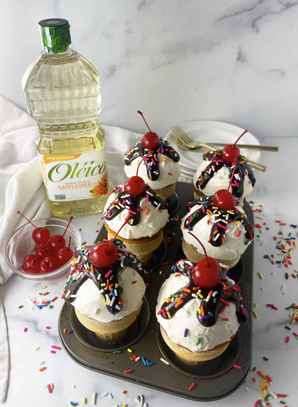 Ice cream cone cupcakes in a muffin pan with Oleico oil bottle in background.