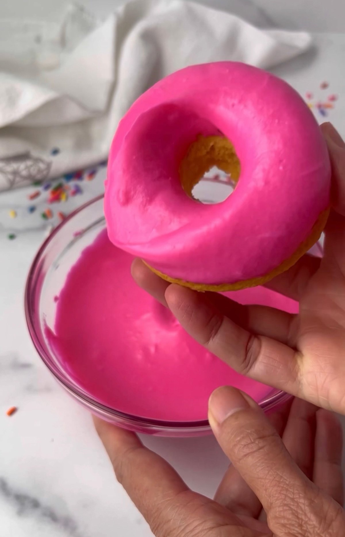 Dipping donuts in pink frosting.