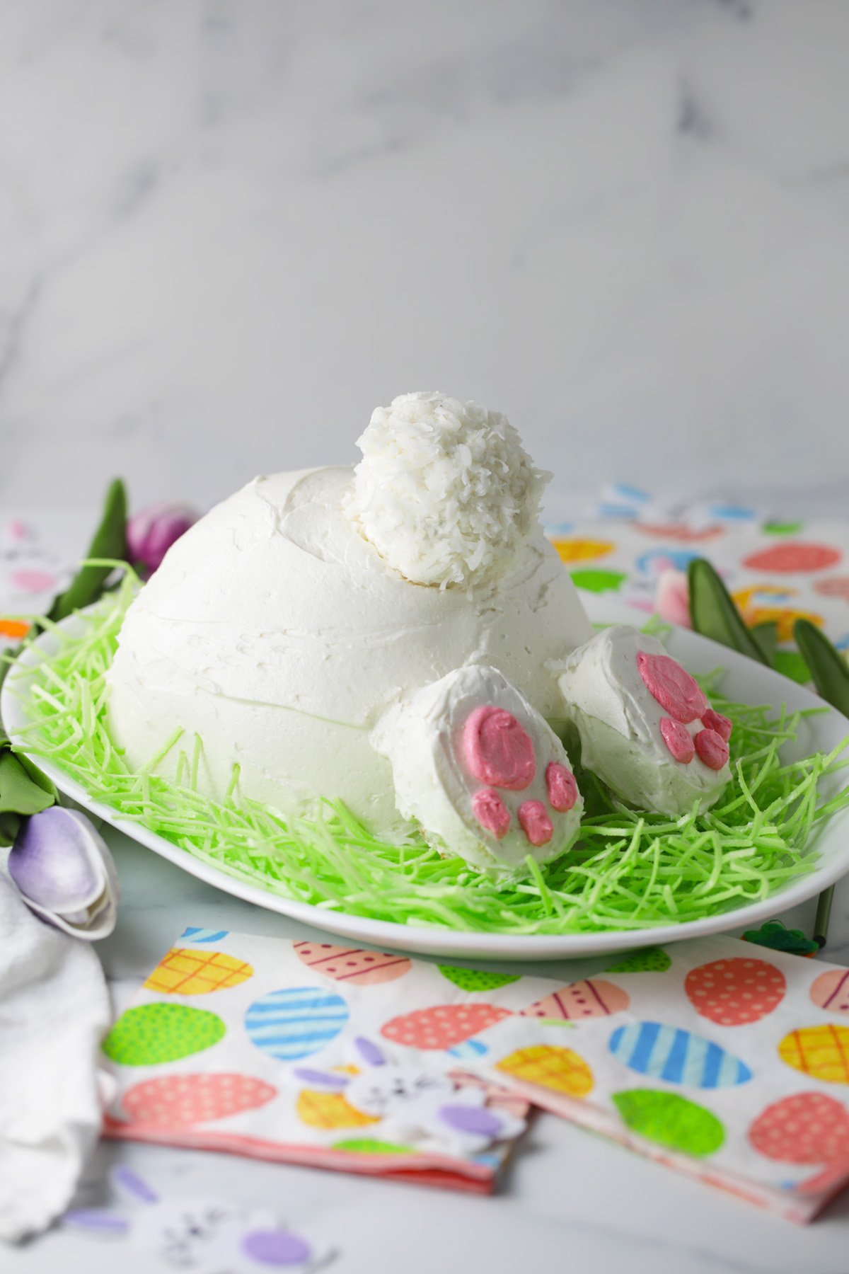 Easter bunny cake on a plate of green colored coconut flakes.