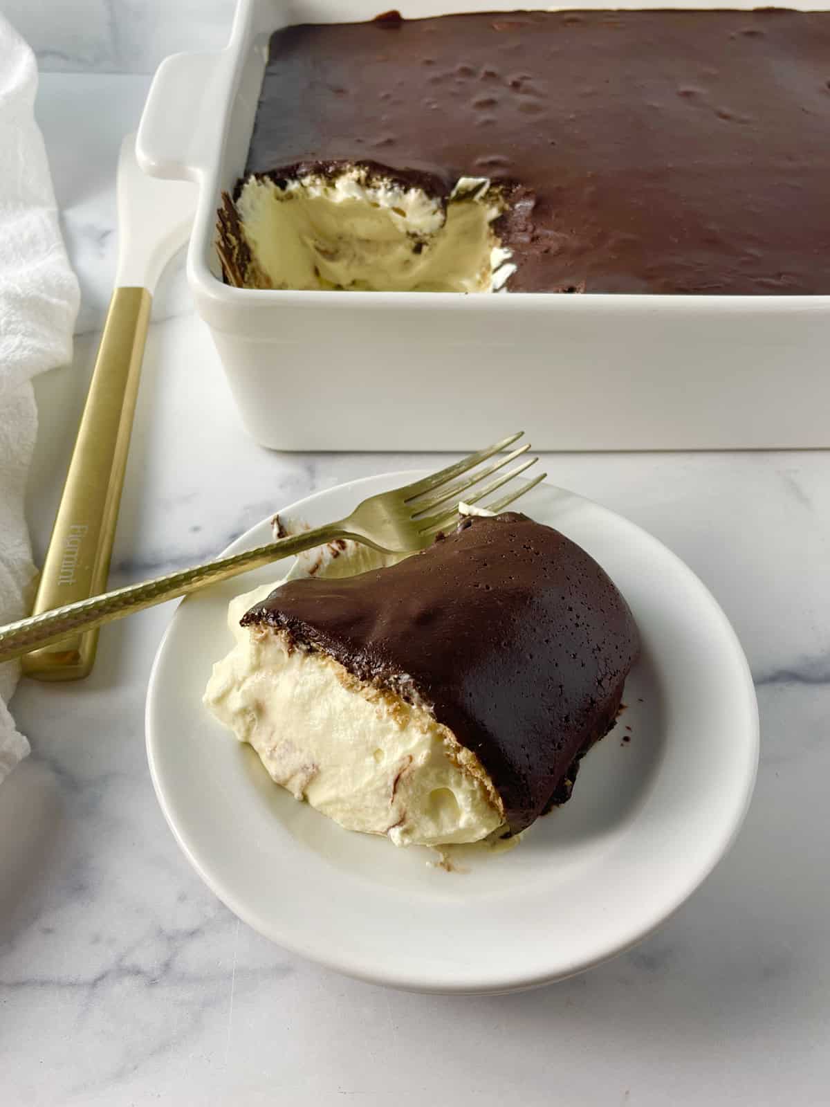 Slice of chocolate eclair cake on a white plate.