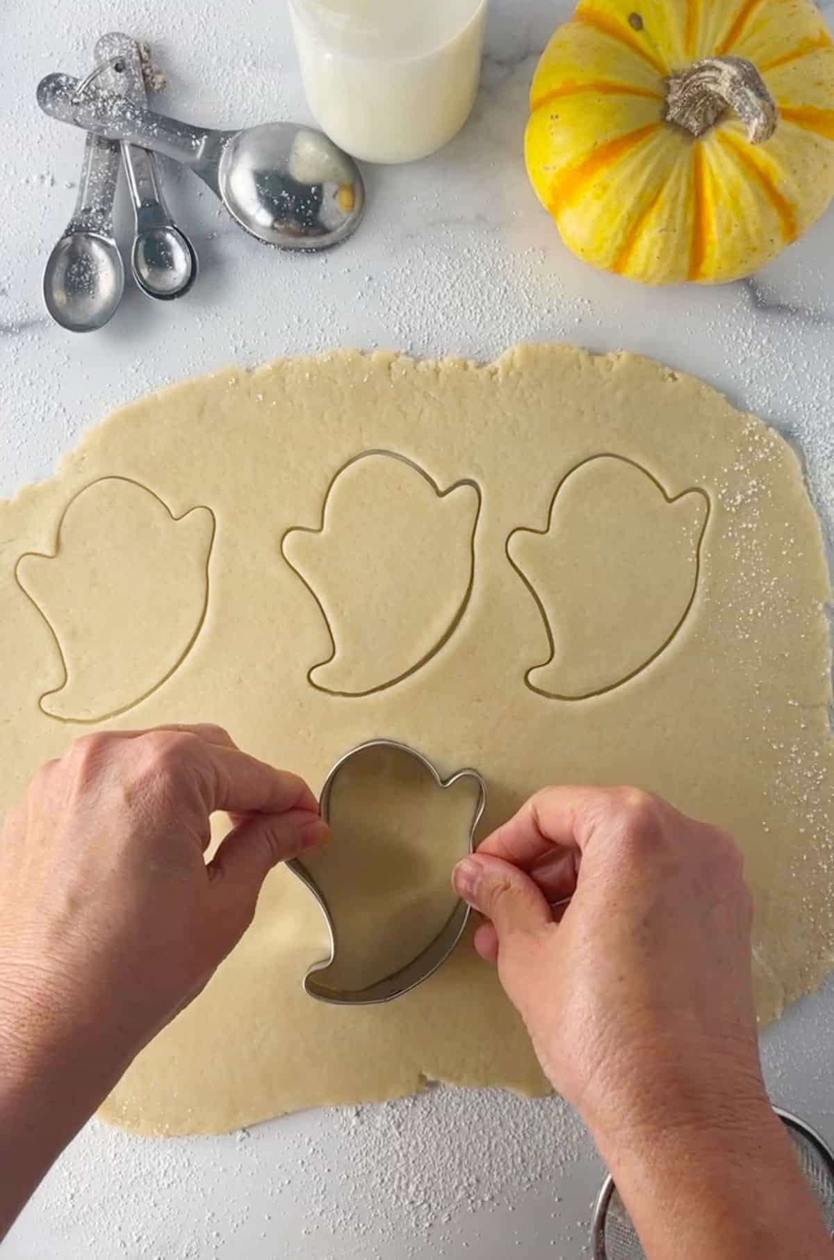 Cutting pie crust dough into ghost cookie cutter shapes.