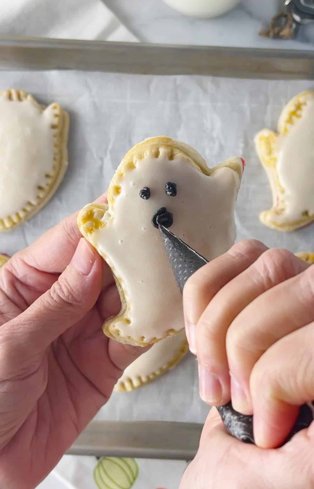 Piping ghost face on pop tart with black icing.