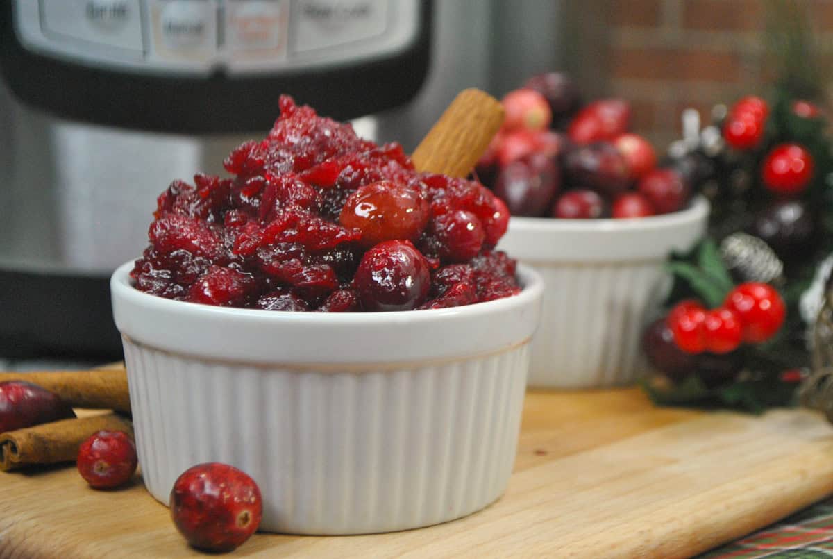 Homemade cranberry sauce in a small white bowl in front of the instant pot.