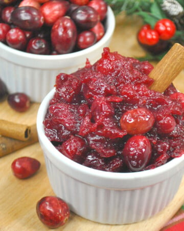 Homemade instant pot cranberry sauce in a small white bowl with cinnamon stick.