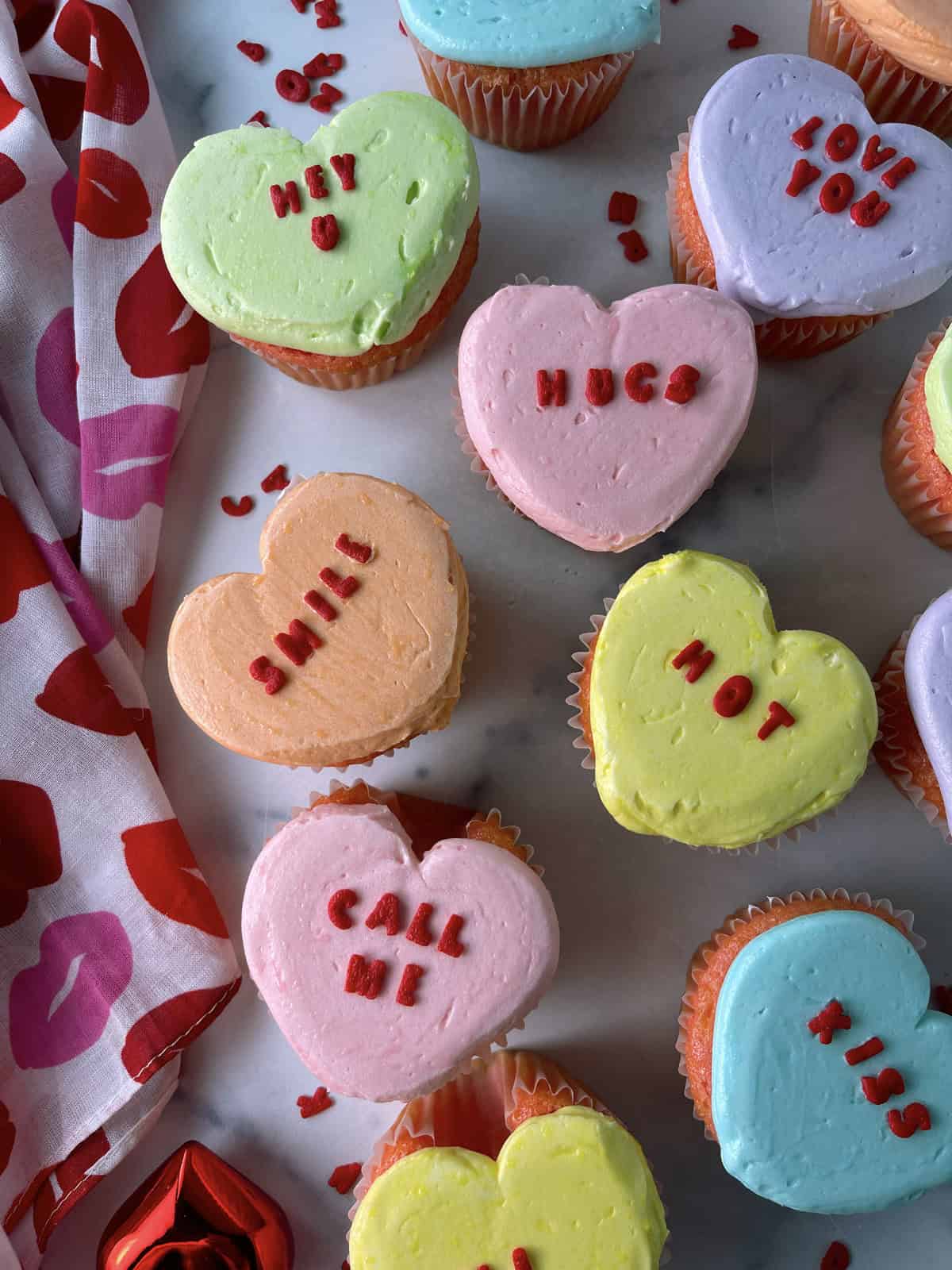 Cute conversation heart cupcakes on the counter.