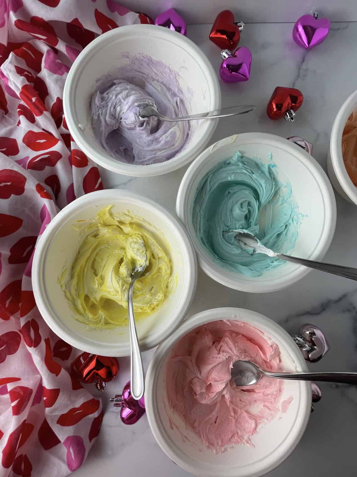 Pastel colored frosting in bowls.