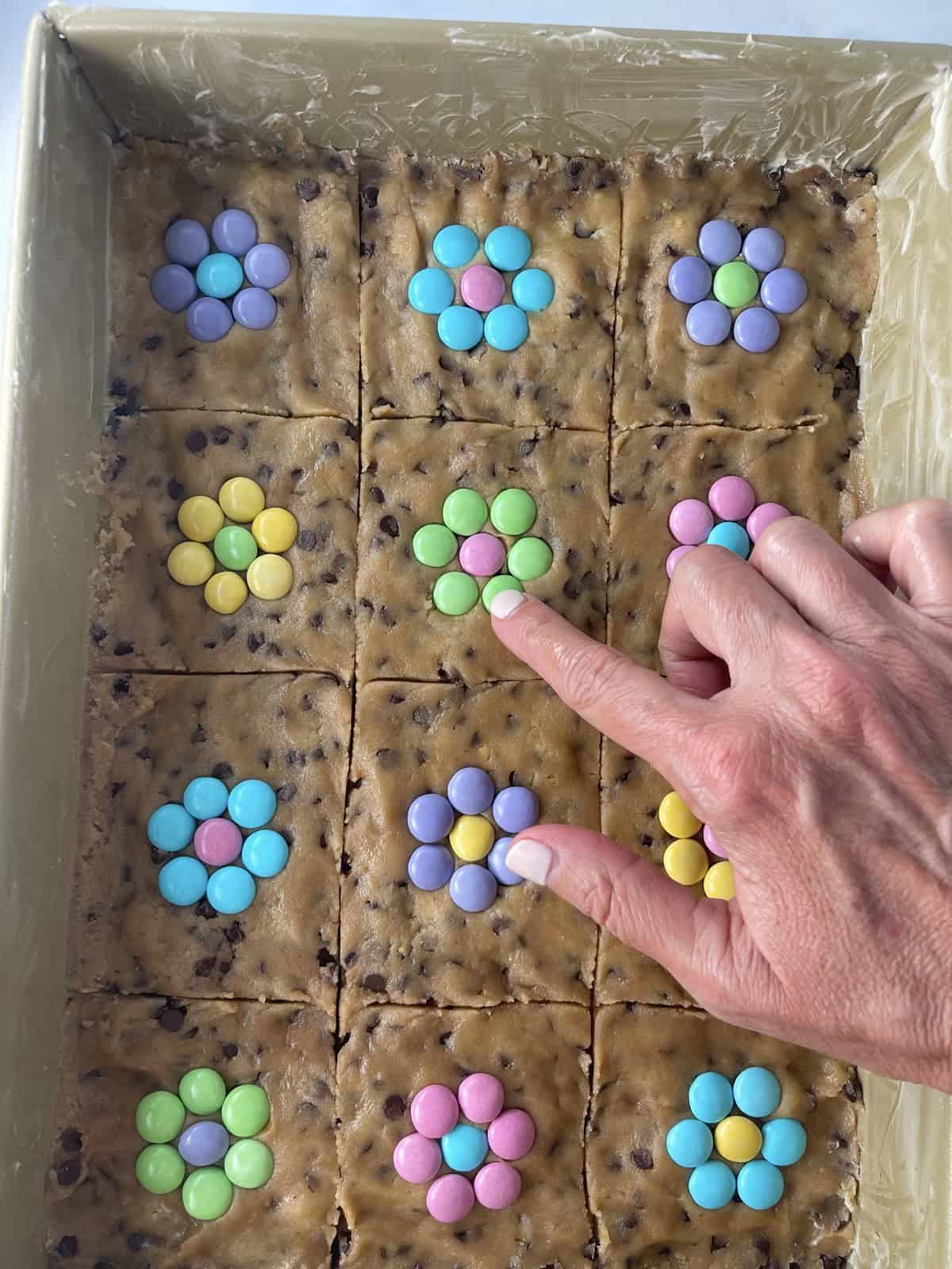 Making m&m flowers on cookie bars.