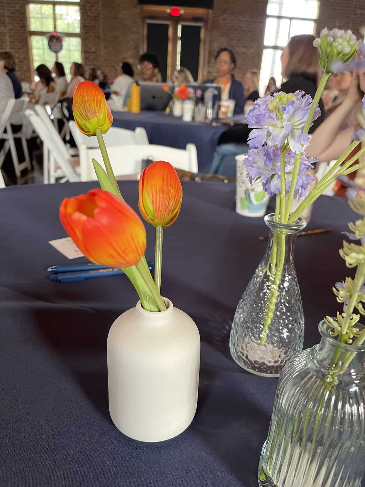 Flowers in a vase on a table with navy table cloth.