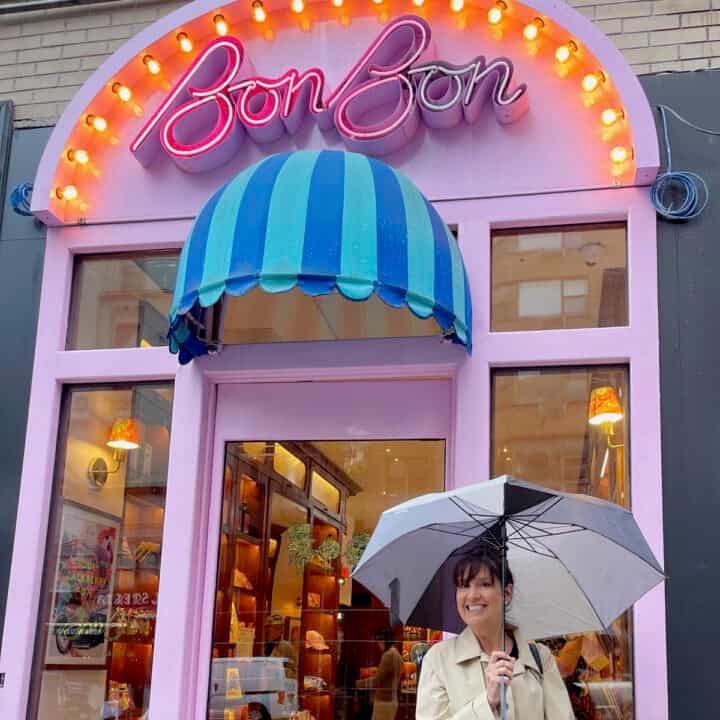 Adorable Swedish candy storefront in nyc with pink door, striped awning and neon lights with food blogger lise ode in front.