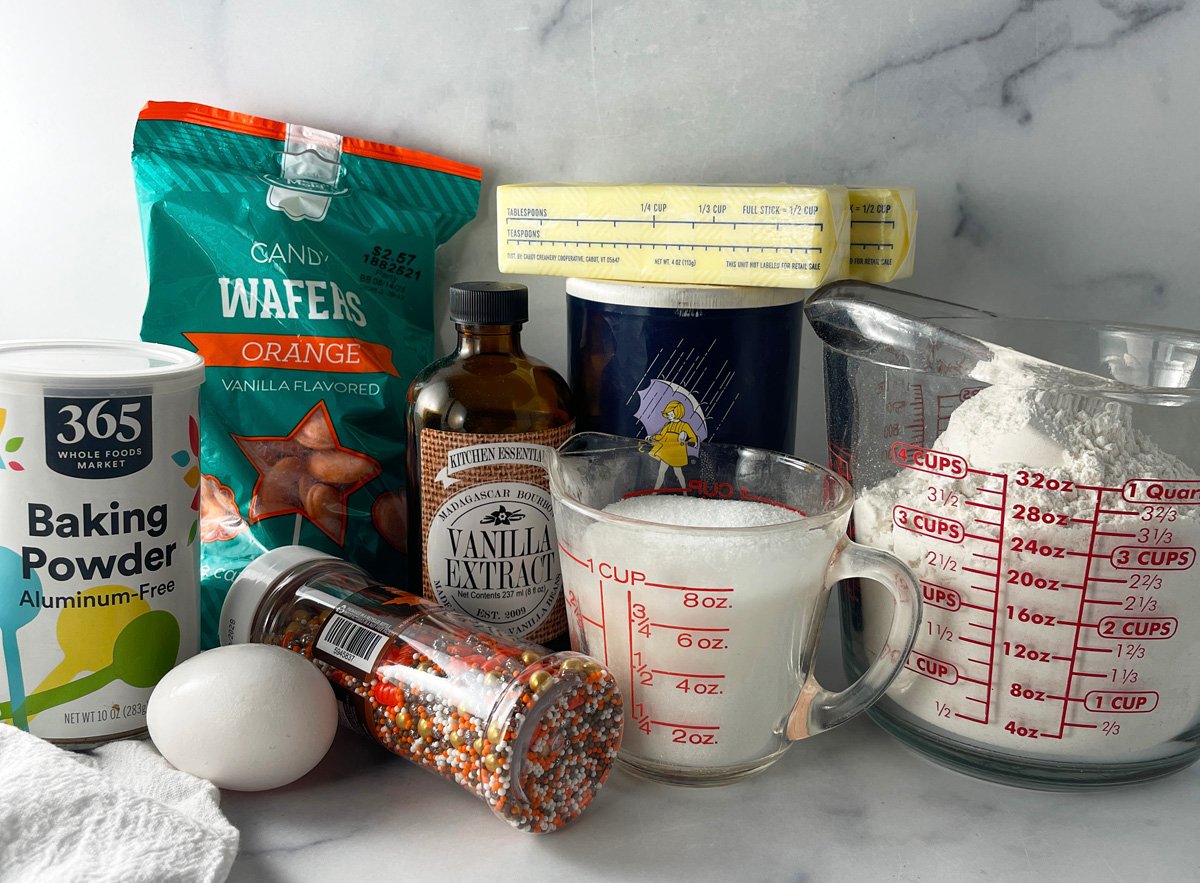Ingredients laid out for making Halloween frosted animal cookies, including cookies, candy melts, and sprinkles.