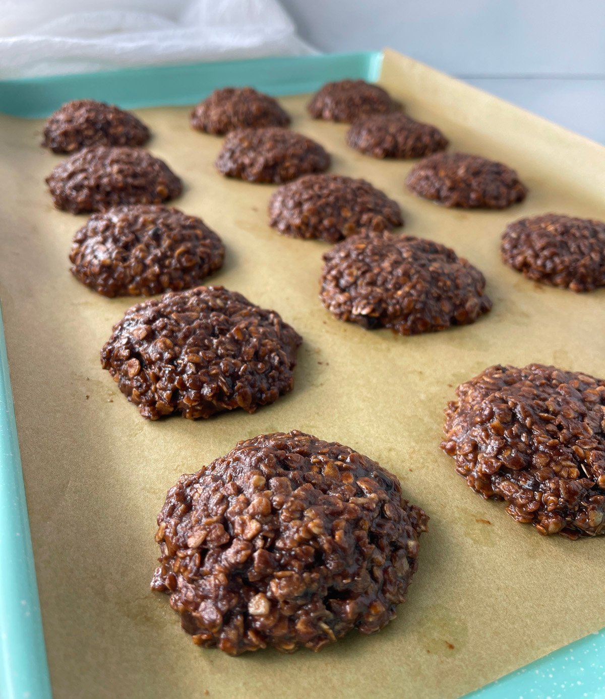 Freshly made no bake chocolate oatmeal cookies cooling on a cookie sheet.