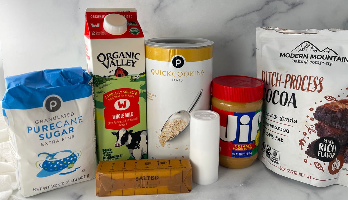 Ingredients for no bake chocolate oatmeal cookies including oats, cocoa powder, butter, sugar, milk, and peanut butter.