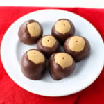 Stack of homemade buckeye candy balls showing smooth chocolate layer and peanut butter top.