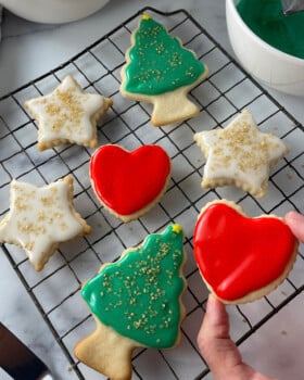Freshly iced sugar cookies drying on a wire cooling rack, topped with glossy glaze icing.