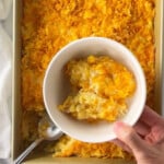 Funeral potatoes casserole served in a white bowl.