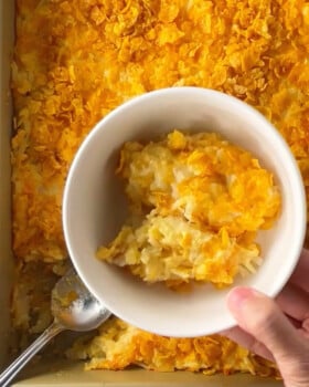 Funeral potatoes casserole served in a white bowl.